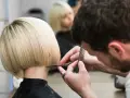 Fryzjerka tworzy modne fryzury odmładzające po 40 krótkie. Blond bob jest precyzyjnie cięty.