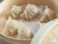 Aksamitne pierożki na parze w bambusowym koszyku, parujące i gotowe do jedzenia.
