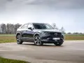 Czarna Mazda MX-30 na tle pochmurnego nieba i drzew.