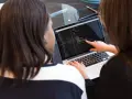 Due persone analizzano codice su un laptop. Una indica una riga, mostrando cosa fa un analista funzionale.