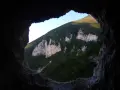 Vista dalla **grotta nera** su un monte verdeggiante con rocce bianche affioranti.