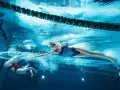 Deux nageuses en action, l'une effectuant une culbute natation, l'autre nageant le crawl sous l'eau.