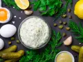Ingredienti freschi per una deliziosa salsa tartara: uova, cetriolini, capperi, limone, aglio, aneto e prezzemolo.