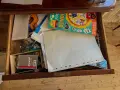 En låda fylld med pysselmaterial, papper, en bok med bondgårdstema och klistermärken, samt en burk med nålar och **påsklämmor**.