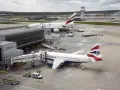 Samoloty British Airways i Emirates czekają na pasażerów na lotnisku Gatwick. W tle widać wieżę kontroli lotów.