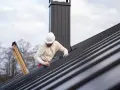 Pracownik na dachu montuje blachę, dbając o szczelność dachu, czy to będzie blacha z filcem czy membrana, ważne by było solidnie.
