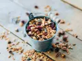 Un cubo metálico lleno de granola casera, con arándanos y semillas. ¡Perfecto para saber como hacer granola!