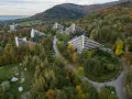 Widok z lotu ptaka na sanatoria o trójkątnej architekturze w otoczeniu jesiennego lasu.