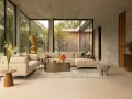 Sofá seccional beige y sillón en un salón moderno con grandes ventanales. Las combinaciones con beige crean un ambiente sereno y elegante.