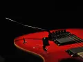 Czerwona gitara elektryczna z czarnym mostkiem tremolo, gotowa do wydobycia dźwięków, które poruszą serce.
