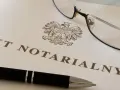 Akt notarialny z orłem, długopis i okulary.