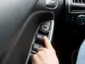 Finger drückt auf Fensterheberschalter. Ein defekter Fensterheber Seilzug reparieren ist oft einfacher als gedacht.