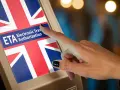 Palec dotyka ekranu z flagą Wielkiej Brytanii i napisem "ETA Electronic Travel Authorization". To krok do uzyskania wizy do Londynu.