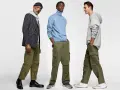 Tres hombres posan con pantalones cargo y camisas. Uno lleva un blazer a rayas, otro un suéter azul y el tercero una sudadera gris.