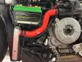 Dettaglio del sistema di raffreddamento motore di una Ducati, con radiatore, tubi rossi e motore in vista.