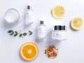 Hudvårdsprodukter från Klairs med C-vitaminserum och en kräm med e-vitamin hud för lyster. Citron- och apelsinskivor som dekoration.