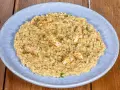 Un cremoso risotto alla crema di scampi, guarnito con scampi scottati e prezzemolo tritato, servito su un piatto azzurro.