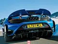 Niebieski McLaren 765LT z czterema końcówkami wydechu pędzi po ośnieżonej drodze w górach.
