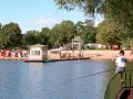 Am Orankesee Strandbad tummeln sich Badegäste, während ein Angler geduldig auf seinen Fang wartet.