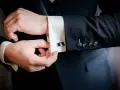 Mężczyzna zapina eleganckie spinki do mankietów koszuli. Dowiedz się, jak zapiąć spinki do koszuli, by wyglądać stylowo.