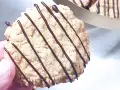 En hand håller en chokladglaserad havrekaka. Perfekt för ett enkelt havrekakor recept.