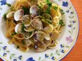 Pyszne spaghetti vongole z małżami i natką pietruszki na talerzu z kwiatowym wzorem.