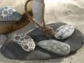 Piedras decoradas con rotuladores, creando patrones circulares y líneas onduladas. Un detalle artesanal para coleccionar.
