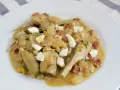 Plato de alcachofas con jamón, huevo duro y piñones, servido en una cazuela.