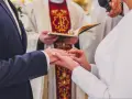 Ceremonia ślubna w kościele. Młoda para wymienia obrączki. W tle ksiądz z księgą. Warto wiedzieć, ile kosztuje ślub kościelny.