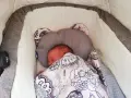 Malutkie dziecko śpi w wózku, otulone kolorowym kocykiem. To pierwszy spacer, czas na drzemkę.