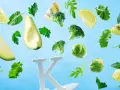 Awokado, brokuły, brukselka, kiwi, cytryna i zielenina unoszą się wokół litery K, symbolizując, w czym jest witamina K.