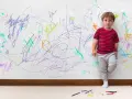 Chłopiec z ADHD, stojący przy ścianie pokrytej kolorowymi bazgrołami, wyraża swoje emocje.