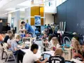 Children engage in 3d printing education, working with laptops and 3D printers in a bright, modern classroom.
