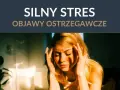 Kobieta zamyka oczy, trzymając się za skronie. Widać wyraźne objawy silnego stresu, takie jak napięcie i ból głowy.