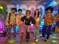 Pięć osób w kolorowych strojach disco z lat 70. na tle napisu "DISCO".