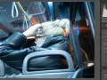 Kobieta w czarnej kurtce siedzi w autobusie, poprawiając włosy. Widać suwaki redukcji szumów w programie do edycji zdjęć.