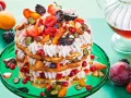 Eine beeindruckende Waffeltorte mit Erdbeeren und Mascarpone, geschichtet mit frischen Beeren und Früchten, auf einem grünen Teller.