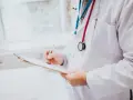 Lekarz w białym kitlu z czerwonym i niebieskim stetoskopem pisze na tablicy.
