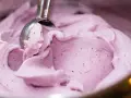 Cremiges Heidelbeereis, perfekt zum Heidelbeereis selber machen. Ein Löffel nimmt eine Portion aus der Schüssel.