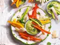 Deliziosi antipasti vegetariani: bastoncini di carote, peperoni e sedano con salsa verde cremosa, guarniti con scaglie di formaggio e menta.