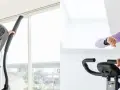 A woman uses a cross trainer while another checks her watch on an exercise bike, showcasing two popular cardio options.