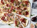 Ein köstlicher Flammkuchen mit Feigen, Schinken und roten Zwiebeln, garniert mit Petersilie.