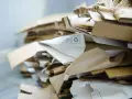 Stos papierowych odpadów, w tym kartony i opakowania, oznaczony jako kod odpadu 15 01 01.