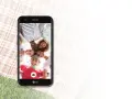 Uśmiechnięta grupa przyjaciół robi selfie telefonem LG K10 2017 Dual na pikniku.
