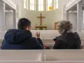 Zwei Menschen im Gespräch in einer Kirche, ein Symbol für die Verbindung von Kirche und Gesellschaft.