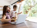 Als alleinerziehende Mutter jongliert sie Arbeit und Kind. Sie telefoniert, während sie ihr Kleinkind hält und am Laptop tippt.