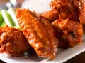 Alitas de pollo en freidora de aire, cubiertas de salsa picante, servidas con bastones de apio crujientes. ¡Un aperitivo irresistible!