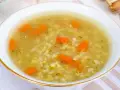 Aromaticzna zupa na rosole z makaronem i marchewką, podana w białej miseczce ze złotym rantem.