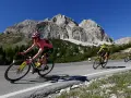 Cyclist in pink jersey, likely the winner of the Giro d'Italia, climbs a mountain road with a dramatic rocky peak behind.