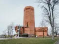 Wysoka, ceglana wieża w mieście, przypominająca mysią wieżę, z kręconymi schodami na zewnątrz.